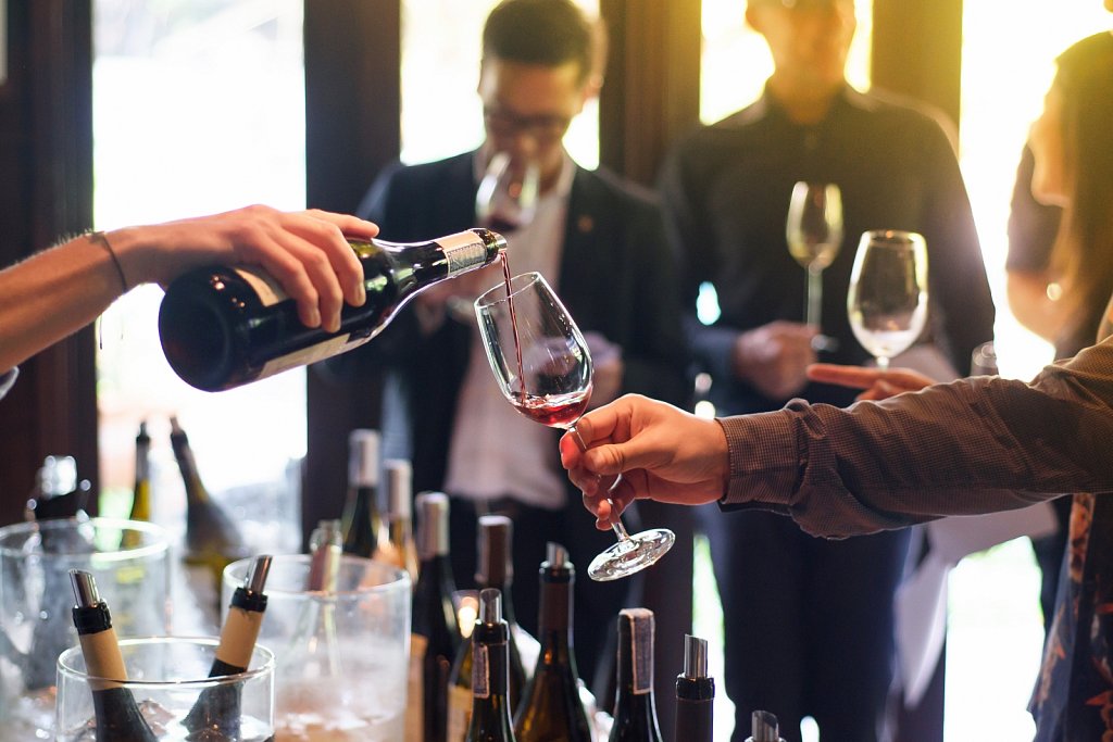 pouring red wine from the bottle into glasses